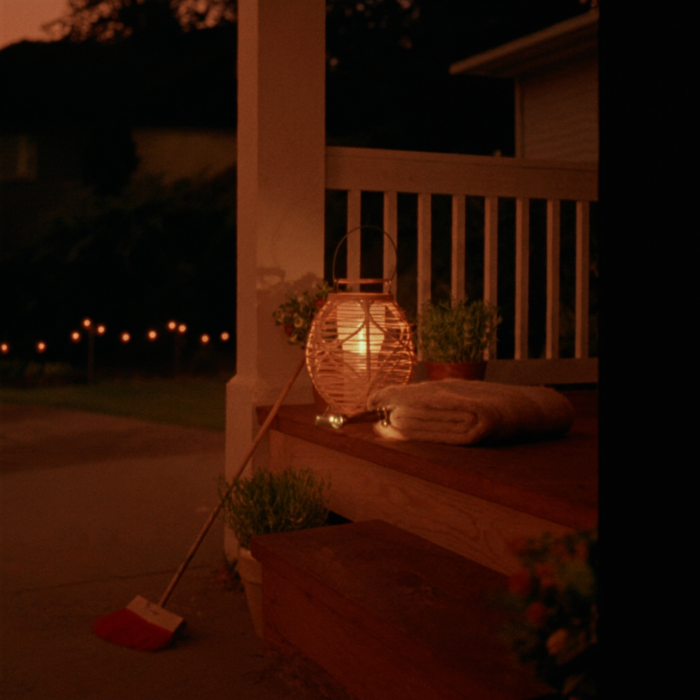 Glowing rattan lantern and flashlight on a porch step at dusk